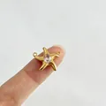 Detailansicht eines goldenen Seesternanhängers mit rosa Strassstein auf einer Fingerspitze - Einzelner Anhänger (Ohne Kette) / Goldener Seestern (Rosa Strass)