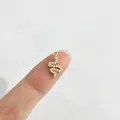 Makroaufnahme eines winzigen goldenen Schlangenanhängers mit Strass auf einer Fingerspitze. - Einzelner Anhänger (Ohne Kette) / Goldene Schlange (Weißer Strass)