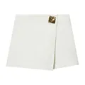 Close-up detail of a white asymmetrical skort featuring a stylish gold metallic buckle - XS / Bottoms / White