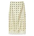 Detailed macro view of a cream midi skirt featuring black polka dots and white lace hem trim - Yellow