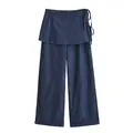 Detailed view of dark wash denim wide-leg trousers with wrap-skirt layer and side ties. - S / Bottoms