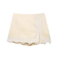 Detail of cream lace patchwork skort with white eyelash lace trim and side slit. - XS / Bottoms / Milk Yellow