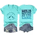 Close-up detail of women's blue V-neck T-shirt featuring 'Life is Better at the Lake' graphic - S / Tops / Deep Water Blue
