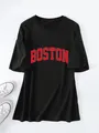 Detailopname van een zwart oversized T-shirt met rode Boston-opdruk en witte sneakers - Zwart