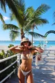 Model trägt einen weißen Pailletten-Bikini auf einem tropischen Holzsteg im Sommerurlaub - S / Oberteil Und Unterteil / Weiß