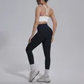 Detail of women's cross back sports bra and black yoga leggings set in studio setting. - White Top And Black Bottom