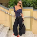 Chic navy blue deep V-neck off-shoulder top styled with wide-leg jeans in outdoor setting. - S / Tops / Navy Blue