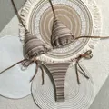 Detail of striped crochet bikini set on woven beach mats with natural sunlight shadows. - S / Top And Bottom / Camel