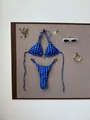 Detail of blue polka dot bikini set pinned on a board with sunglasses and flowers - S / Top And Bottom / Blue