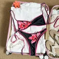 Flachbild eines Retro-Floral-Bikinis im rosa Koffer mit Sommerreise-Accessoires. - S / Oberteil Und Unterteil / Schwarzrosa