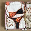 Zweiteiliger Bikini mit Blumenstickerei im rosa Koffer mit Urlaubsaccessoires präsentiert. - S / Oberteil Und Unterteil / Schwarz Orange