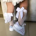 Detailed view of girls' white fishnet knee-high socks with oversized bow embellishments - One Size (3-12 Years) / White
