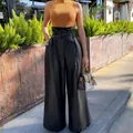 Model wearing black high-waisted PU leather wide-leg pants with a matching belt. - S / Bottoms / Black