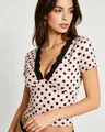 Dettaglio del top rosa a pois da donna con bordo in pizzo nero sullo scollo a V - Rosa