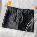 Detail showing a retro black PU leather mini skirt with decorative belt and front zipper - S / Bottoms / Black