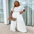 Détail de la texture plissée de l'élégante combinaison blanche à jambes larges et ceinture - S / Blanc