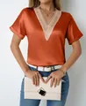 Close-up view of elegant V-neck satin blouse featuring intricate lace trim detailing - Orange