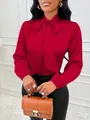 Détail en gros plan d'un chemisier en satin rouge avec un élégant col à nœud papillon - S / Hauts / Rouge