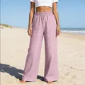 Vue de face d'un pantalon en denim rose à jambes larges sur un fond de plage ensoleillée - S / Bas / Rose