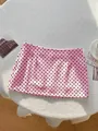 Detail shot of pink polka dot mini skirt on textured background - S / Bottoms / Pink