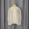 Detalle de blusa blanca de gasa con lazo en cuello y mangas abullonadas transparentes. - S / Tops / Albaricoque