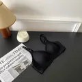 Gedetailleerd zicht van een naadloze zwarte draadloze bh in een gezellige kamer. - M / Tops / Zwart
