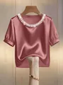 Nahaufnahme eines eleganten Satin-Kurzarm-Oberteils mit dekorativem Perlenausschnitt - Rosa