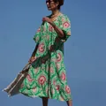Lebhaftes Kleid mit geometrischem Muster und Puffärmeln in einer modischen Außenumgebung. - Florales Grün
