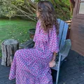 Detailansicht eines lila geometrischen Maxikleids mit Puffärmeln in einem Garten. - Cyan