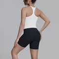Achteraanzicht van witte racerback sporttop en zwarte sportbroek op een vrouwelijk model. - Wit en Zwart
