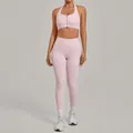 Two-piece pink yoga set featuring a zip-front halter sports bra and high-waisted leggings. - Sakura Pink