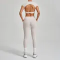 Back view of a light beige two-piece yoga set featuring an open-back top and high-waist leggings - Warm Stone Grey