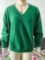 Close-up of the V-neckline and texture of a green knitted pullover on a mannequin form - Green