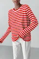 Detailed view of women's red and white horizontal striped crew neck knit sweater on model - Orange Red