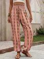 Detailed view of women's pink geometric print lantern pants featuring a smocked waist - Orange