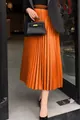 Jupe midi plissée orange à taille haute, avec un drapé élégant et des détails plissés fins. - S / Bas / Orange
