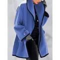 Gros plan d'un manteau en laine bleue avec d'élégants liserés noirs contrastés et coupe ample. - Bleu