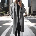 Detail shot of a women's grey oversized long wool coat styled in a modern city street - S / Tops / Gray