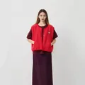 Gilet polaire rouge sans manches porté sur un haut sombre et une jupe par un mannequin - Rouge