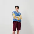 Femme en gilet polaire bleu sur un pull duveteux à rayures et un short bordeaux, style décontracté. - Bleu