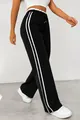 Detail of black wide-leg sweatpants with white side stripes worn by a model walking - S / Bottoms / Black
