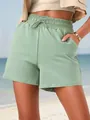 Detail view of sage green drawstring casual shorts with pockets on model. - Light Green