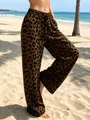 Detailed view of women's leopard print casual wide-leg pants against a sunny beach background - S / Bottoms / Dark Brown