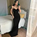 Detail view of an elegant black floor-length slip dress on a model in a bedroom. - S / Top And Bottom / Black