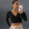 Detalle de un top corto negro de manga larga con cuello en V y tejido acanalado - S / Tops / Negro