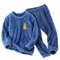 Detail van zachte blauwe flanellen kinderpyjamaset met schattig dinosaurusborduursel - 110 / Boven- En Onderstuk / Blauw