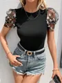 Detail eines schwarzen Slim-Fit-T-Shirts mit bestickten transparenten Puffärmeln. - S / Oberteile / Schwarz