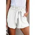 Detail view of white paperbag waist shorts with tied belt and pleated pockets for women. - White