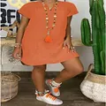 Detailed view of an orange loose V-neck short sleeve woven dress on a model - Orange