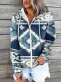 Detailopname van een damesvest met blauwe tribale print en rits op een houten wand. - S / Tops / Cyaan